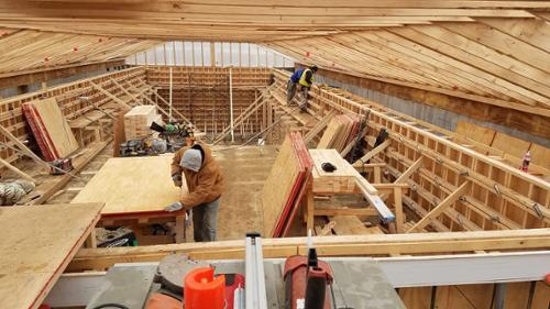 The concrete contractor is hard at work with performing carpentry for the formwork, for this swimming pool, currently under constuction.. The roof structure in this image is a temporary structure, to provide shelter from the elements during constuction.